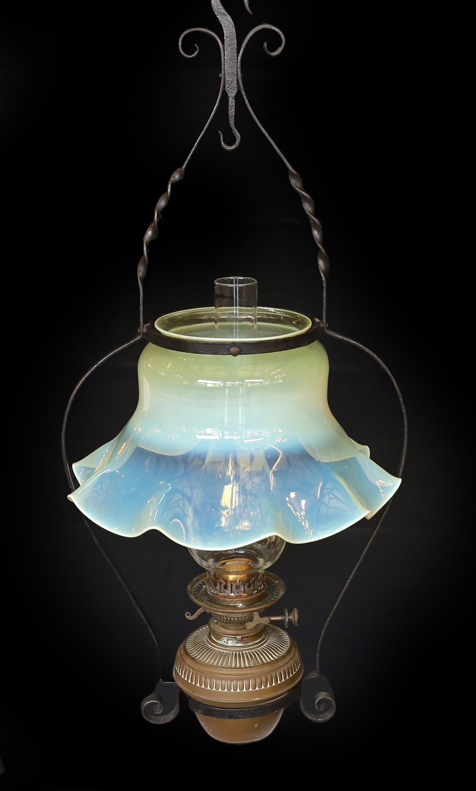 An English Arts & Crafts wrought iron and brass hanging oil lamp with Messengers mechanism and frilled Vaseline glass shade, height 86cm. diameter 40cm